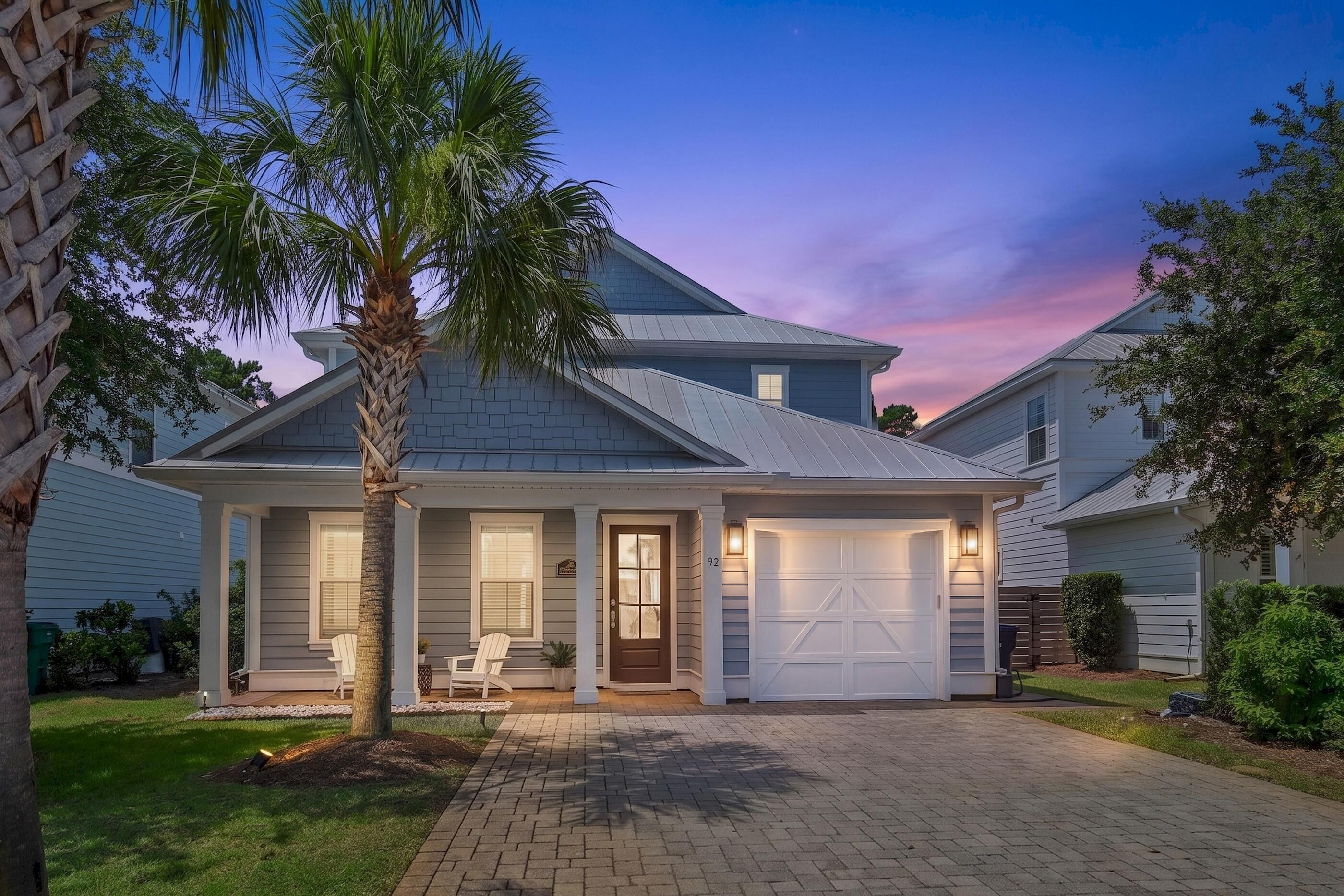 A two-story house with a garage, a covered porch, and a well-maintained lawn.