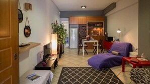 A compact living space with a kitchenette, a dining area, and a seating area with a sofa and a small table. - "The Grey" in Mets (Athina)