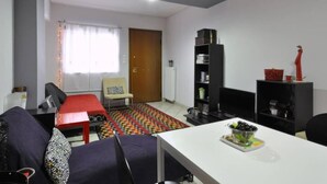 A modern living room with a sofa, a coffee table, a TV, and a bookshelf. - "The Grey" in Mets (Athina)