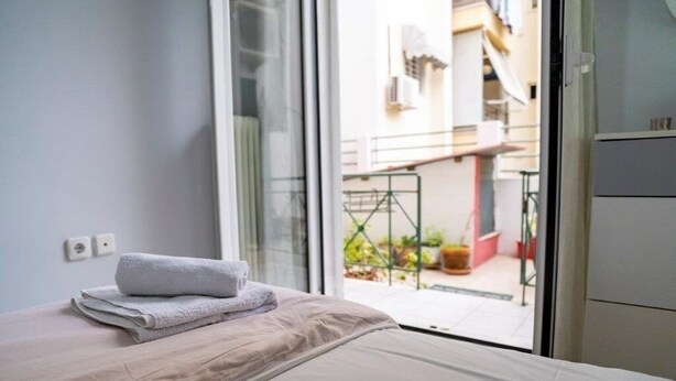 A hotel room with a bed, a window, and a view of the outside balcony. - "The Grey" in Mets (Athina)