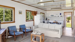 A compact living space with a sofa, two chairs, a small coffee table, and a kitchenette in the background. - 29 Ocean Road, Brooms Head (Brooms Head)