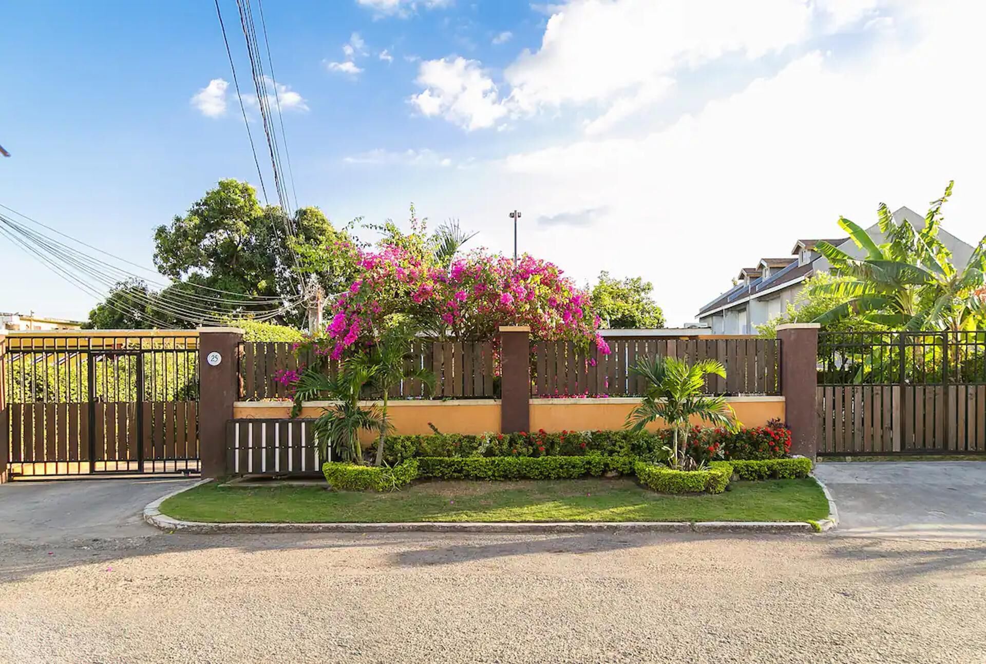 A gated residential area with a well-maintained lawn, a fence, and flowering plants.