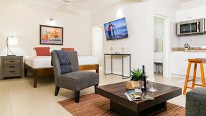 Ein modernes Wohnzimmer mit einer Couch, einem Couchtisch, einem Fernseher und einer Küchenzeile inklusive Mikrowelle.