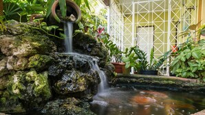 Ein kleiner Wasserfall in einem Garten mit Steinen und Pflanzen.