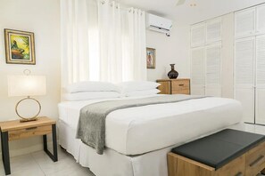 A neatly arranged bedroom with a bed, bedside tables, a bench, and a wardrobe. - Pines Serenity Suites in Kingston 6 (Kingston)