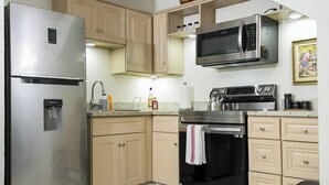 Une cuisine moderne dotée d’appareils électroménagers en acier inoxydable, de meubles de couleur beige et d’un escalier en bois.