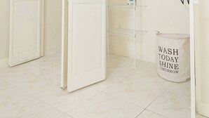 Un dressing blanc, avec les portes ouvertes, une tringle à vêtements et un sac à linge portant une inscription.