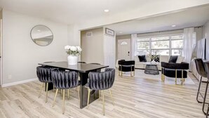 Ein modernes Wohnzimmer mit Essbereich, das einen schwarzen Esstisch mit vier Stühlen, eine Couch und einen Couchtisch zeigt.