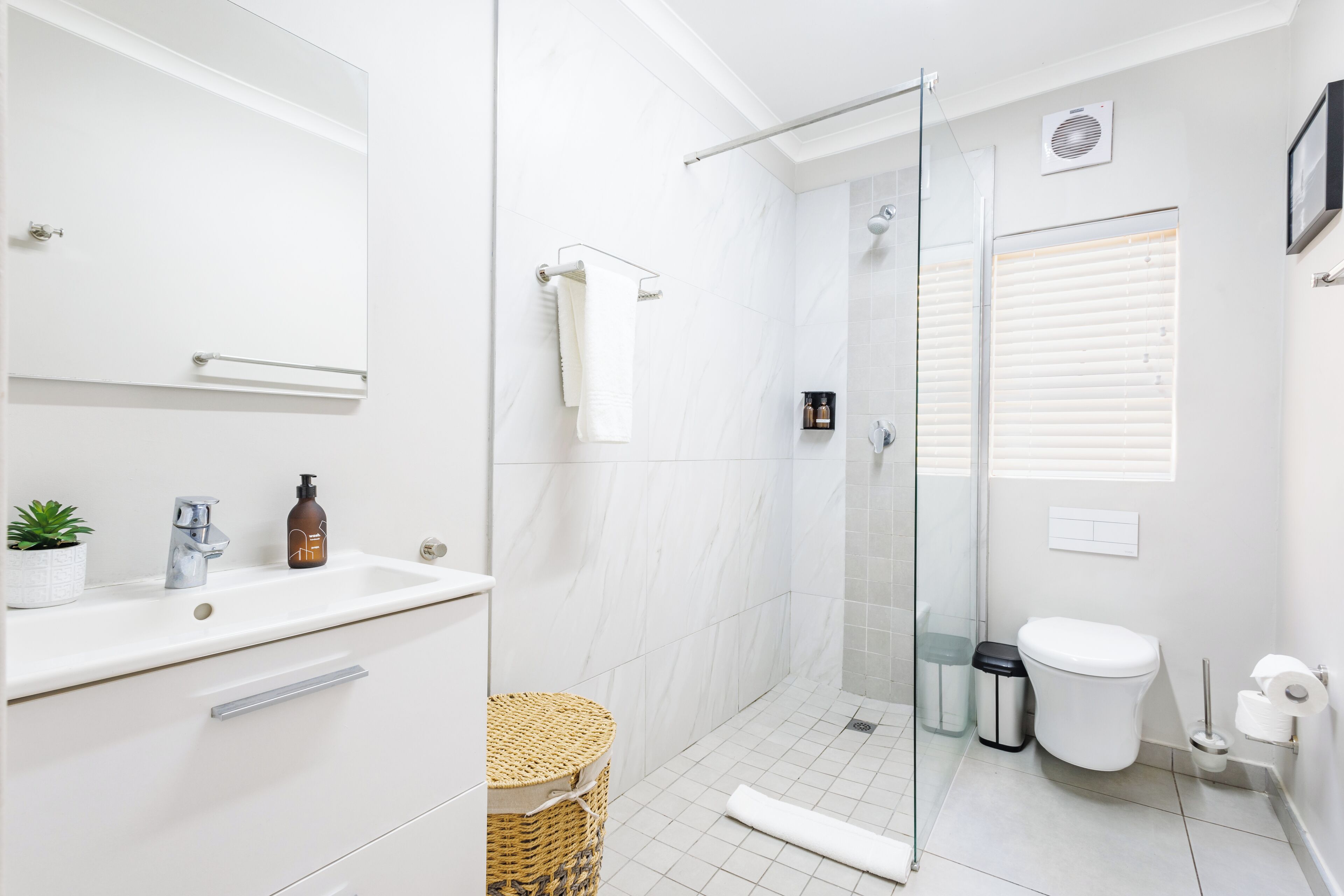 Une salle de bain moderne avec une douche à parois de verre, un lavabo blanc avec un miroir et des toilettes.