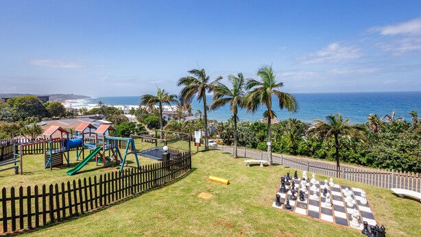 Un parque con juegos infantiles, un tablero de ajedrez y vistas al océano.