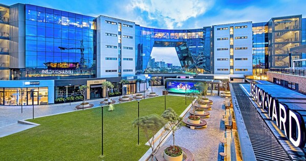 A modern hotel with a central courtyard, outdoor seating, and a large digital screen.
