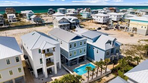 A coastal residential area with multiple two-story houses, a swimming pool, and a beach in the background. - Serendipity Cottage (Navarre)