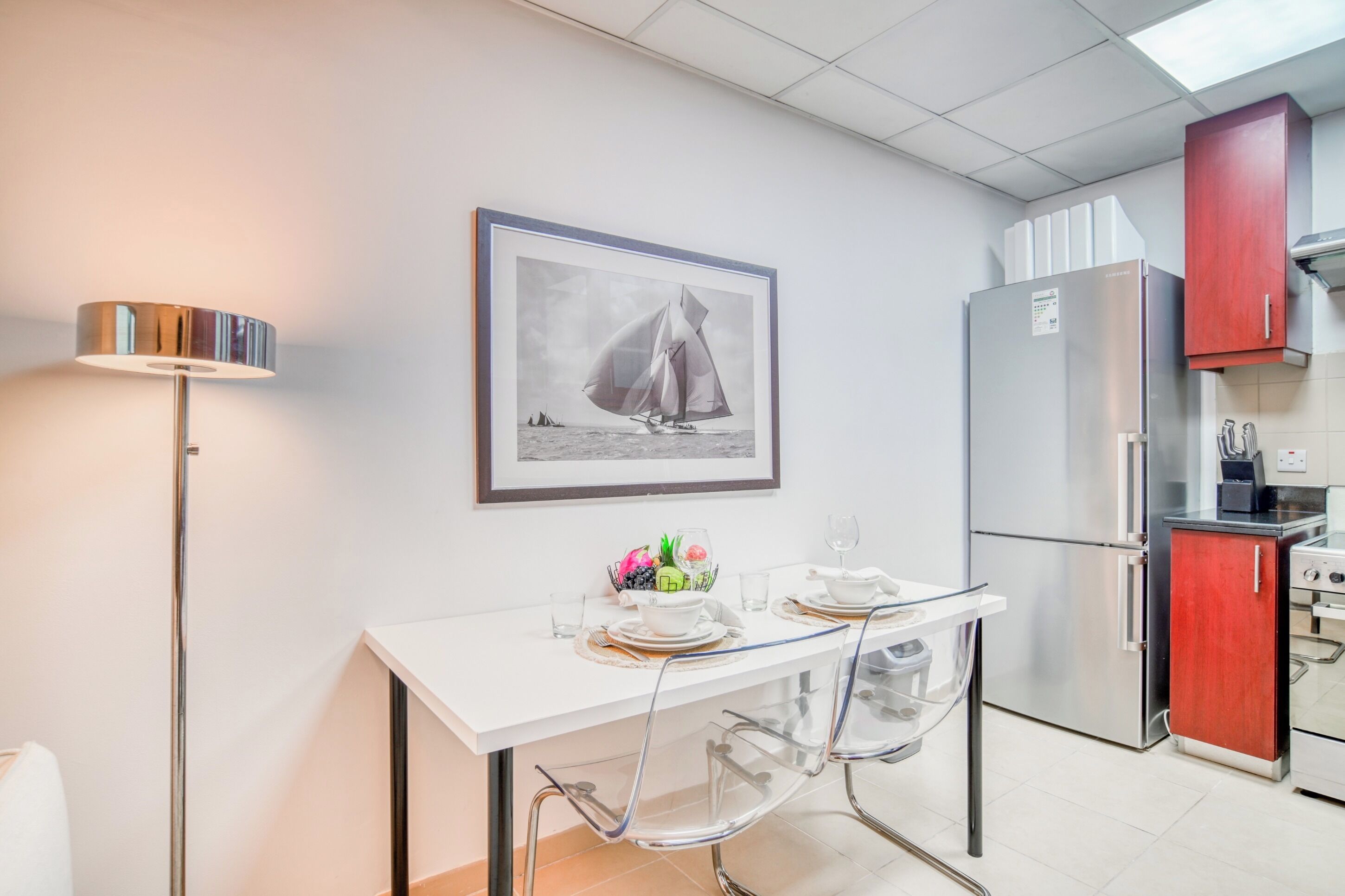 Una cocina moderna con una mesa de comedor para dos personas, un refrigerador y una estufa.