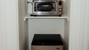 Una kitchenette compacta con microondas, horno tostador y refrigerador pequeño.