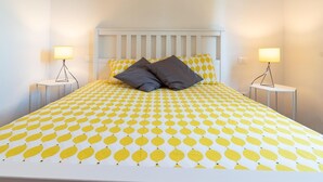 A bed with a patterned bedspread, two bedside tables with lamps, and a white headboard. - Pescara INN at Golf - Tiger Woods (Abruzzo)