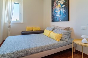 A bedroom with a bed, a bedside table, a window with curtains, and a painting on the wall. - Pescara INN on the Gulf - Tiger Woods (Abruzzo)