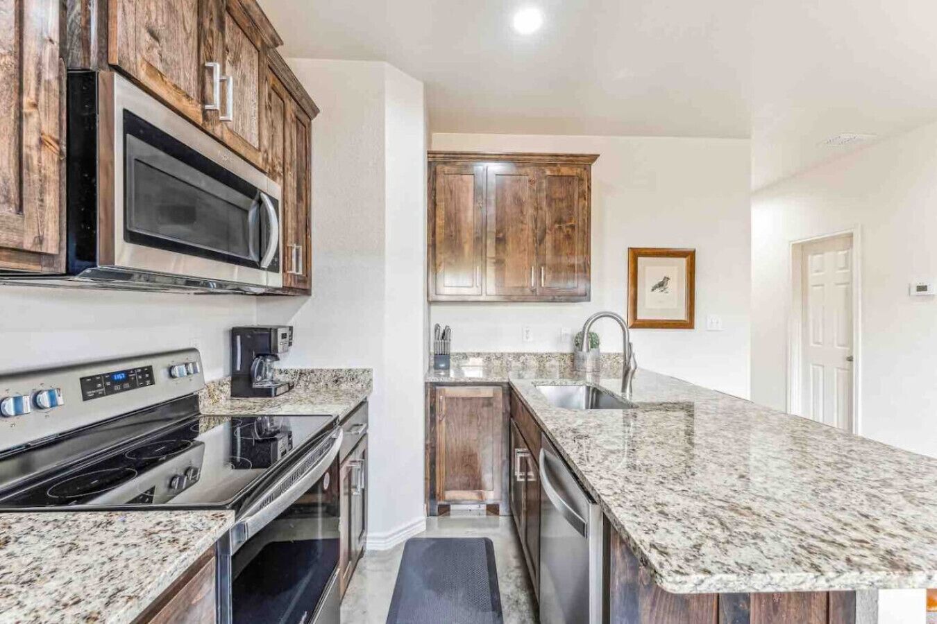 A kitchen with granite countertops, stainless steel appliances, wooden cabinets, and a built-in microwave.