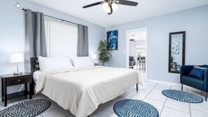 A bedroom with a bed, nightstands, a ceiling fan, and a view of the dining area. - Cozy Getaway with Pool and Putting Green - Unit 2 (Fort Lauderdale)