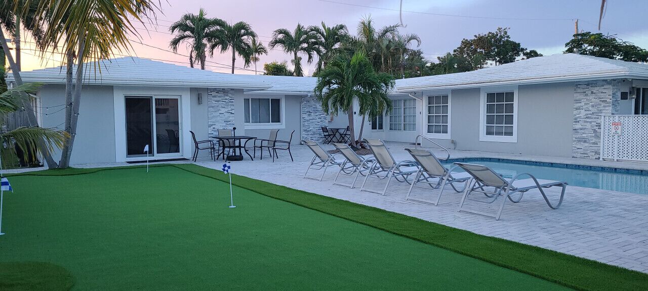 A pool area with a green lawn, lounge chairs, and a pool.