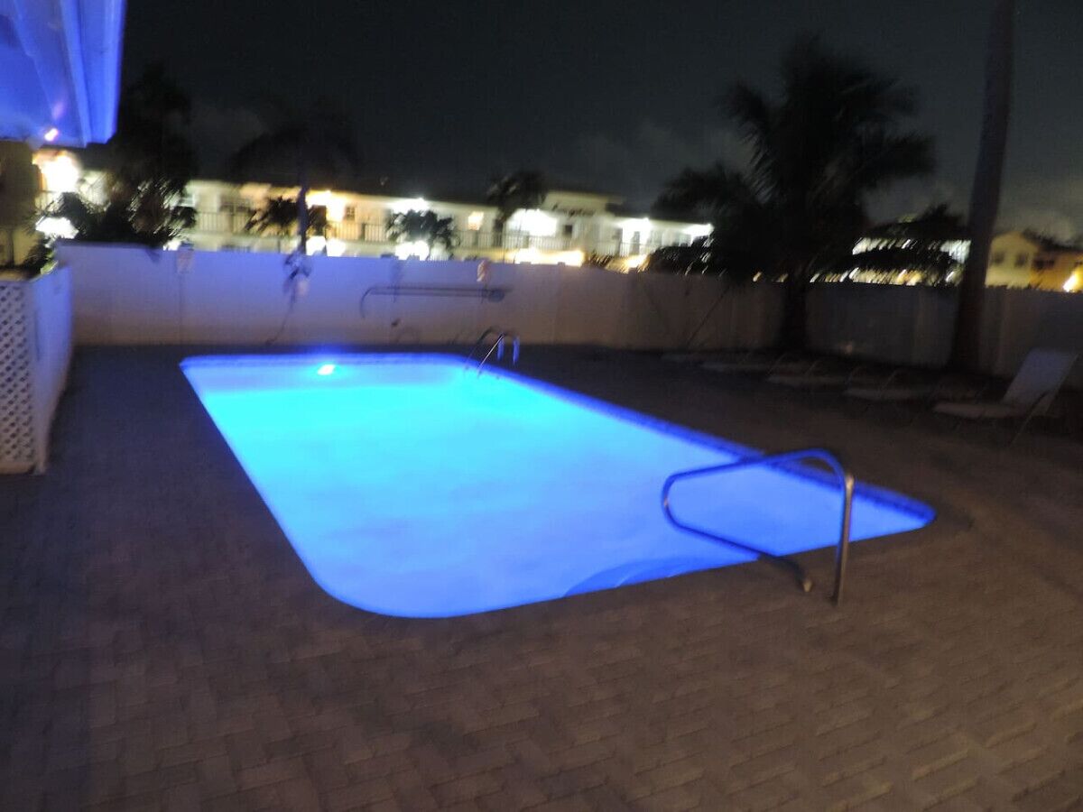 Ein rechteckiger Pool mit einer Leiter an einer Seite, umgeben von einer Pflasterterrasse.