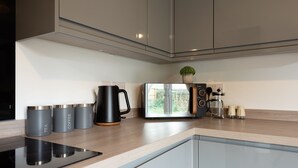A modern kitchen with a built-in induction cooktop, a coffee maker, and a toaster. - Spacious 5-Bedroom House in Nottingham (Nottingham)