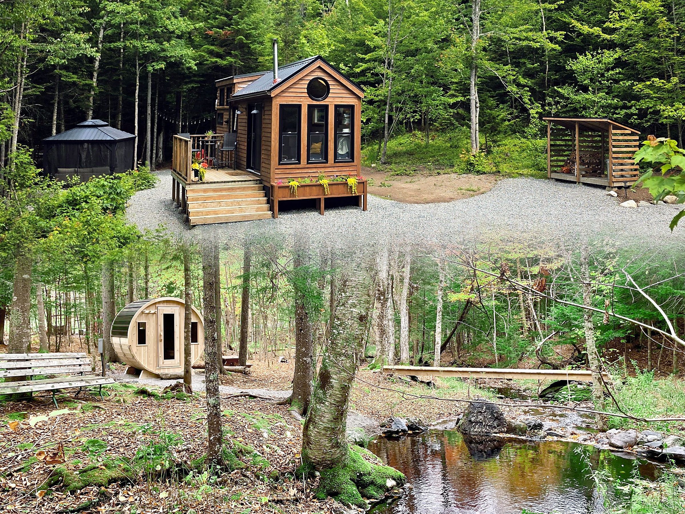 A cabin with a deck and a small pond in a forested area.