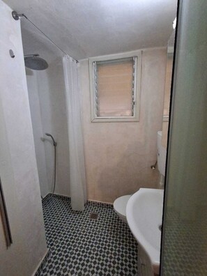 Une petite salle de bain avec une douche, des toilettes et un lavabo.