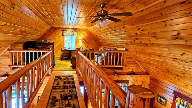 Un intérieur en bois avec un escalier central, un ventilateur de plafond et une fenêtre offrant une vue agréable.