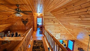 Un intérieur en bois avec un escalier central, des rampes en bois et un ventilateur de plafond.
