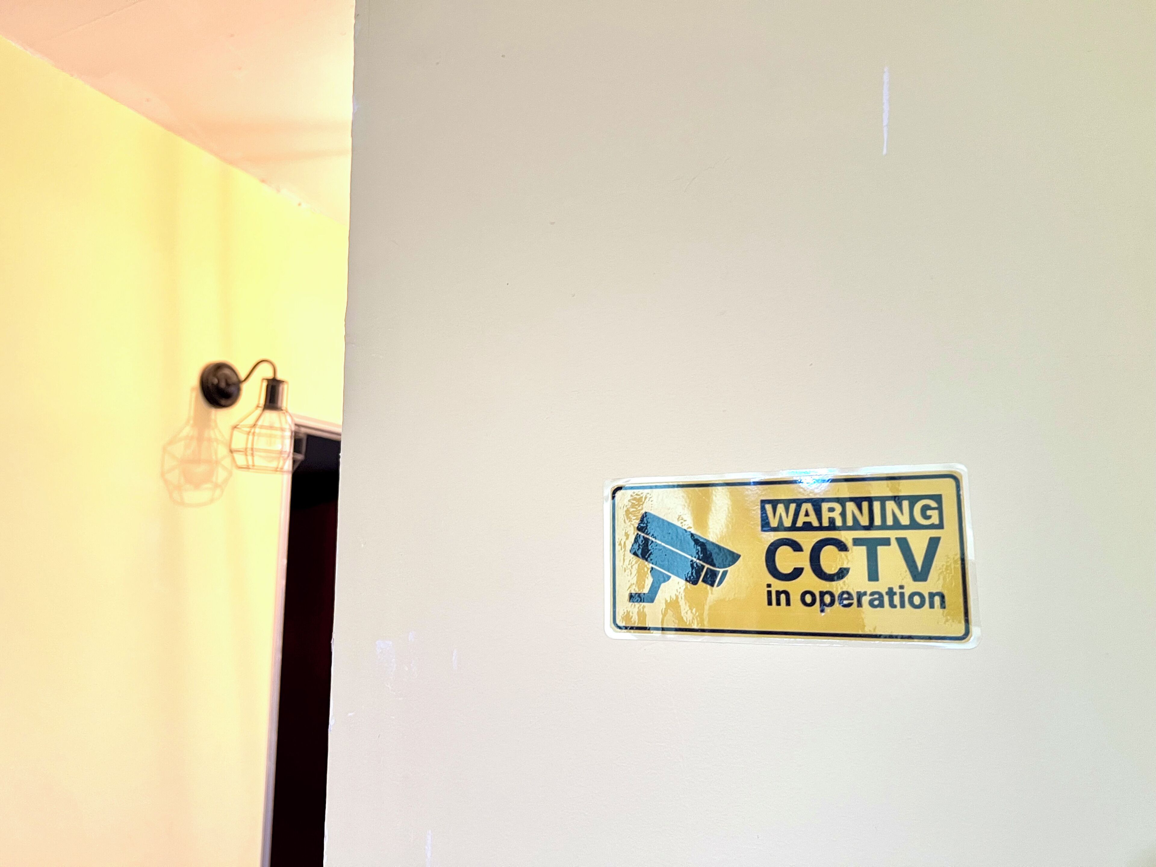 A door with a warning sign indicating CCTV is in operation.