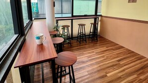 Un intérieur moderne avec une table et des tabourets en bois, de grandes fenêtres et des luminaires suspendus.
