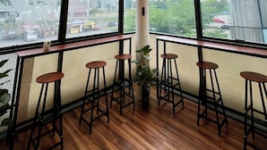 Un intérieur moderne avec un ventilateur de plafond, de grandes fenêtres, un plancher en bois et des tabourets de bar.
