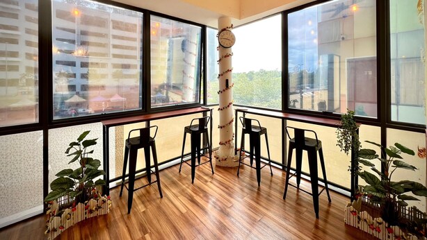 Une pièce spacieuse avec de grandes fenêtres, un plancher en bois et des chaises noires.
