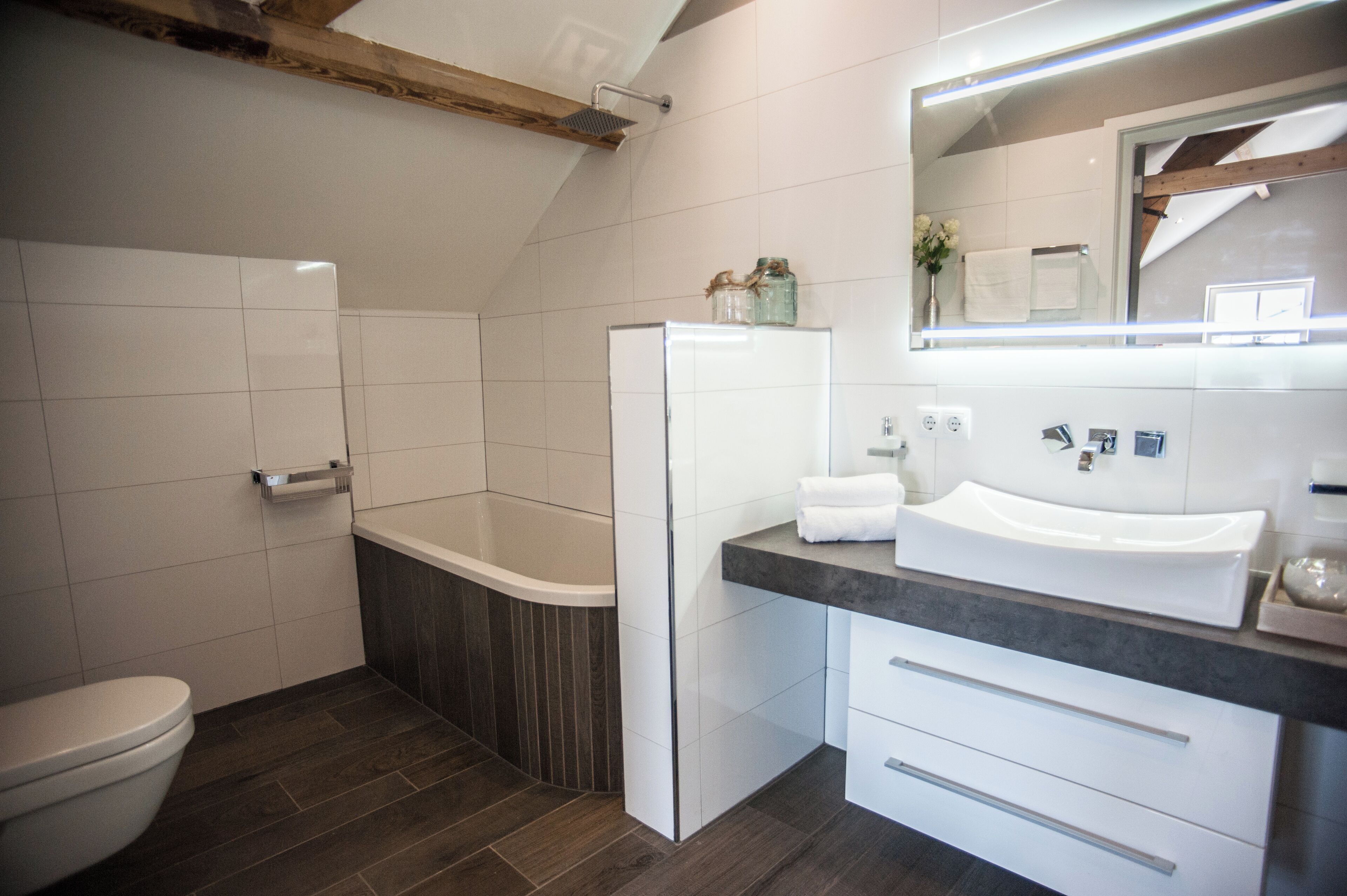 Une salle de bain moderne équipée de toilettes, d’une baignoire et d’un lavabo avec un miroir.
