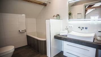 Une salle de bain moderne équipée de toilettes, d’une baignoire et d’un lavabo avec un miroir.