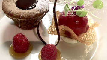 A dessert plate with a chocolate cake, a berry dessert, and two raspberries.