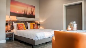 Un dormitorio con cama, mesita de noche, una mesa con frascos y un cuadro en la pared.