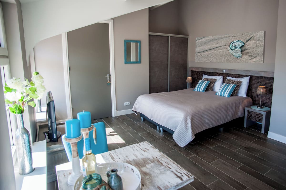 A bedroom with a bed, bedside tables, a mirror, and a wall-mounted artwork.