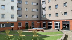 A courtyard with a picnic table and chairs, surrounded by a multi-story building with a brick facade and multiple windows. - For Students Only Canvas The Heights in Birmingham (Birmingham)