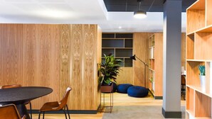 A modern office space with a wooden wall, a round table with chairs, a potted plant, and a bookshelf. - For Students Only Canvas The Heights in Birmingham (Birmingham)