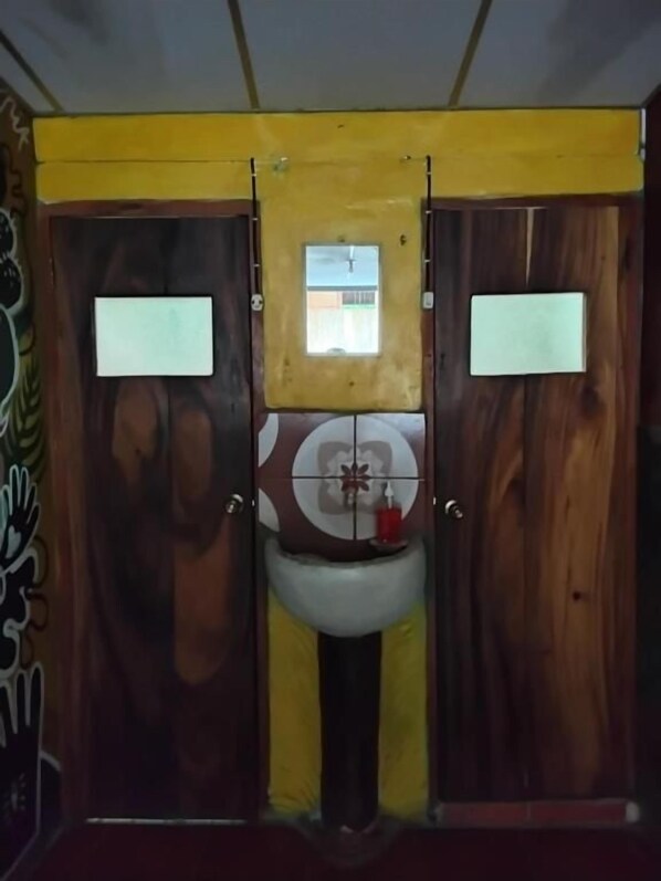A bathroom with two wooden doors, a central sink, and a small window above the sink.