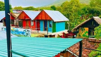 A view from a covered area overlooking colorful buildings with a mountainous landscape in the background.