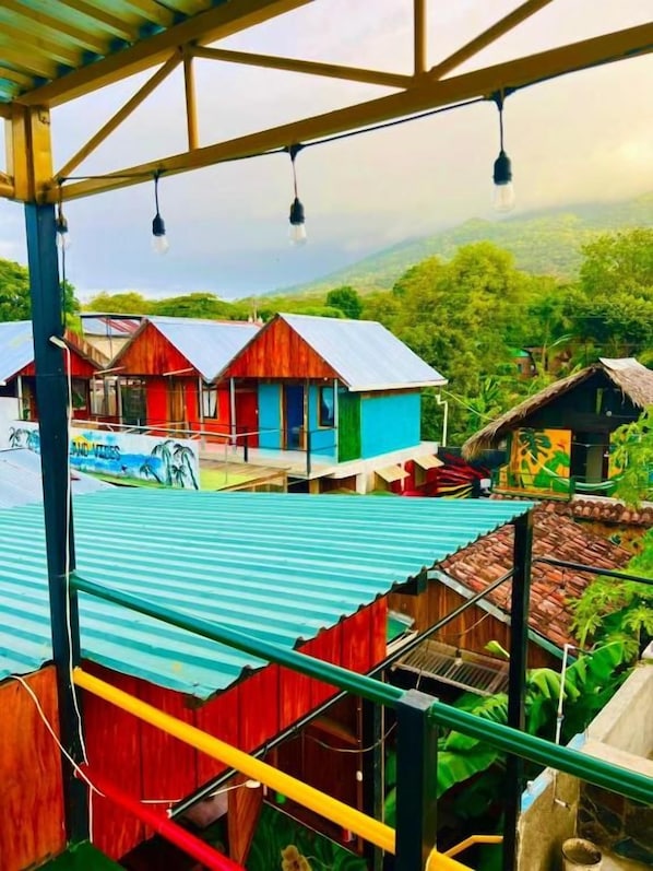 A view from a covered area overlooking colorful buildings with a mountainous landscape in the background.