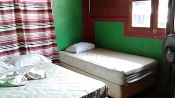 A room with two beds, a window with curtains, and a fan.