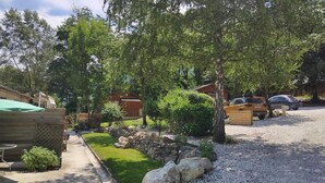 Un barrio residencial con camino de grava, cerca de madera y un pequeño jardín con rocas y plantas.