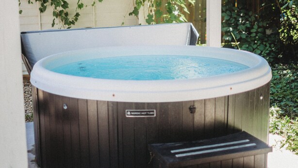 A hot tub with steps leading up to it, surrounded by a wooden deck and covered patio. - Cozy Nook by Lake MI&Dunes with Private Hot Tub! (Harbert)