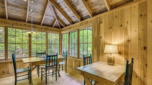 Una baita in legno con zona pranzo, che include un tavolo, sedie e una lampada.