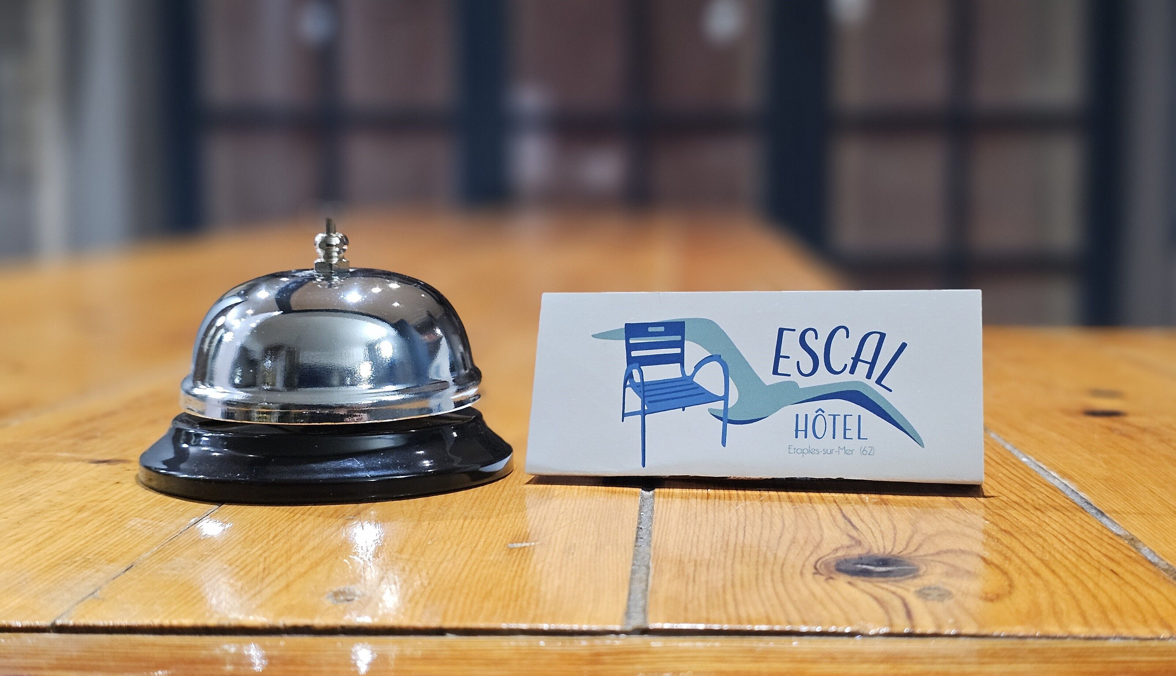 Un rètol d'hotel amb una cadira i una campana sobre una taula de fusta.