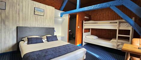 A bedroom with a large bed, a bunk bed, wooden walls, and a blue ceiling beam.