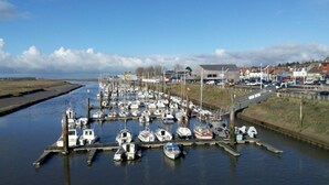 A marina with numerous boats docked at wooden piers, surrounded by a small town with houses and a clear sky. - ESCAL'HOTEL (Etaples)